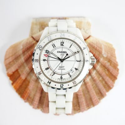 a white watch sitting on top of a seashell