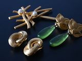gold and green earrings and brooches on a black surface