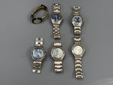 trois montres et une bague sont posées sur une table