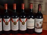 six bottles of red wine are lined up on a table