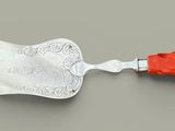 une spatule argentée et rouge avec un manche rouge