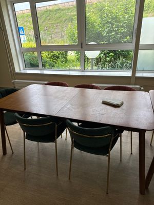 une table avec quatre chaises et une télécommande devant une fenêtre