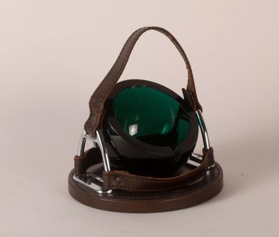a green bowl sitting on top of a brown holder