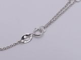 a close up of a silver chain with a heart on it