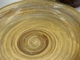 a brown plate with a swirl on it next to a brown vase