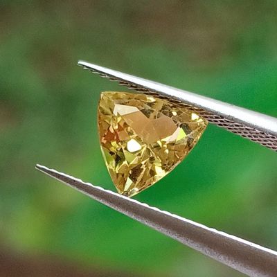 a close up of a yellow diamond being held by a pair of pliers