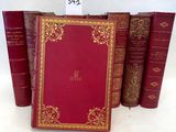 trois livres en cuir rouge, avec des bordures dorées et des inscriptions dorées
