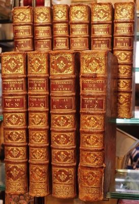 Plusieurs vieux livres sont empilés sur une étagère en verre dans un magasin