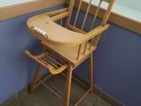a wooden high chair with a wooden seat in the corner of a room