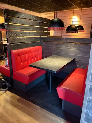 une cabine rouge avec une table noire et des chaises rouges