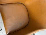 two brown leather chairs sitting next to each other on a tiled floor