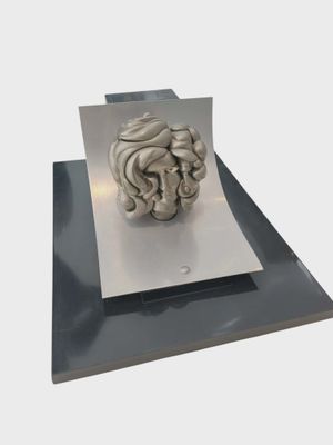 une sculpture représentant une tête humaine posée sur une feuille de papier