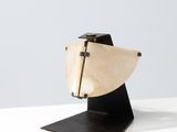 sculpture en bois représentant un bateau, posée sur un socle noir, sur une surface blanche