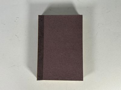 une image représentant un livre marron posé sur une table blanche