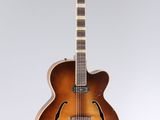 a brown guitar sitting on top of a white surface