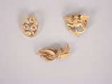 three gold brooches and a broochle on a white surface