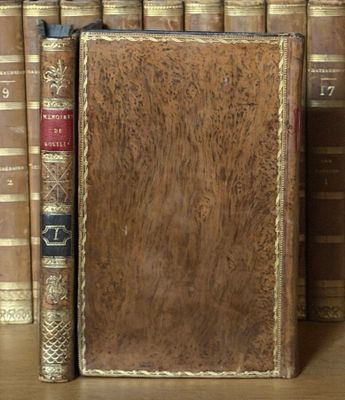 un livre posé sur une étagère, devant une pile de livres