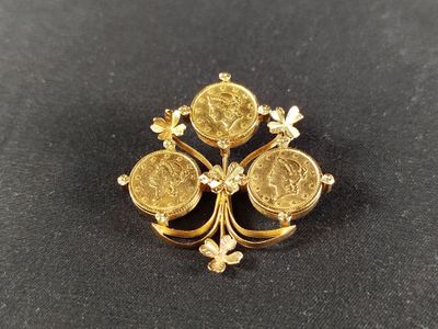 un gros plan d'une broche en forme de pièce d'or posée sur une surface noire