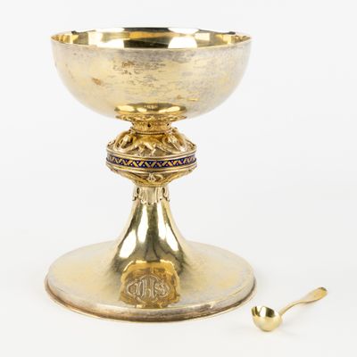 tasse plaquée or avec cuillère et repose-cuillère, posée sur un support blanc