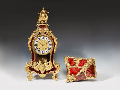 une petite horloge posée à côté d'une petite boîte sur une table