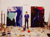 a man that is standing in front of some paintings