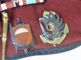 a red hat with a red ribbon and some badges on it