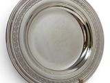 an antique silver plate on a stand on a white surface
