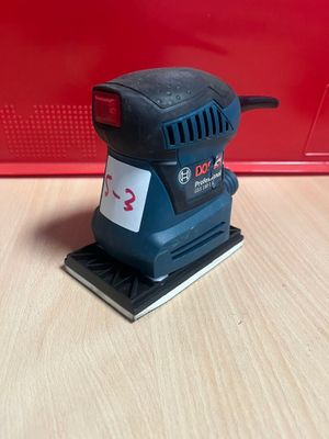 une ponceuse orbitale Bosch sur une surface en bois