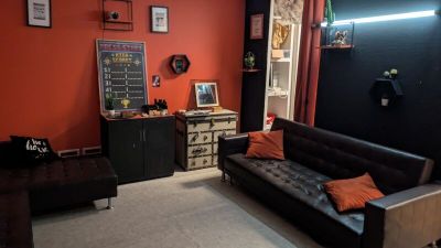 un salon avec un canapé noir et un mur rouge