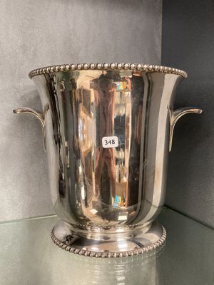 un vase en argent posé sur une étagère en verre dans une pièce