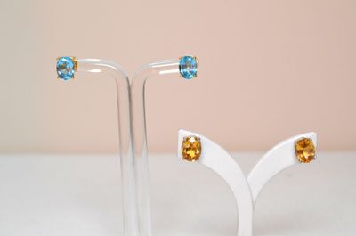 pair of blue topaz and yellow topaz crystal earrings on a white stand