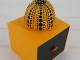 une petite boîte orange surmontée d'une citrouille noire et jaune