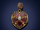 a close up of a gold pendant with red stones and pearls