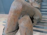 a statue of a naked woman sitting on a bench