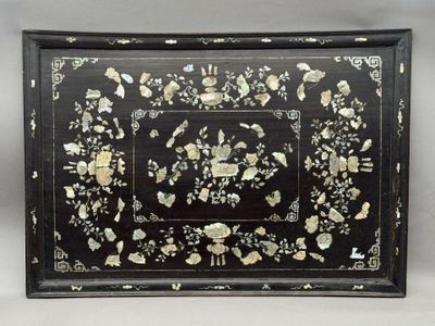 une image représentant un plateau noir et doré orné de fleurs et de feuilles