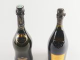 two bottles of champagne sitting next to each other on a white surface