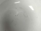 a white bowl with a black spot in it