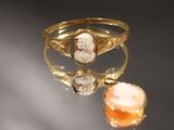 une image représentant une bague en or ornée du portrait d'un homme et d'une pierre orange