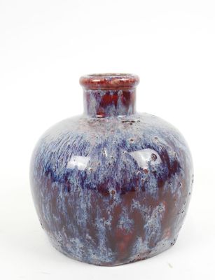 un vase bleu et rouge posé sur une surface blanche