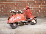a red scooter that is parked in front of a brick wall