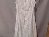 the white dress is hanging on a hanger on the wall