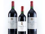 three bottles of red wine sitting next to each other on a white surface