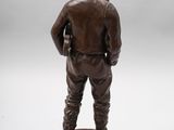 a statue of a man with a hat and boots standing on a pedestal
