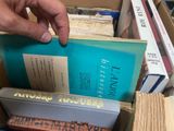 a person holding a book in a box full of books