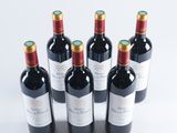 six bottles of red wine lined up in a row on a white surface