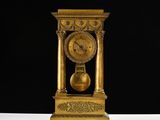 une horloge dorée posée sur une table, sur fond noir