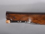a close up of a rifle with a wooden handle on a white surface