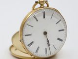a small gold clock with roman numerals on it