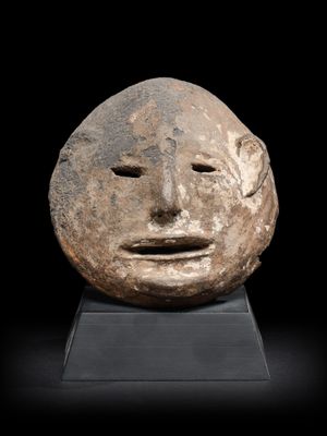 une tête d'homme sculptée dans la pierre, sur un fond noir