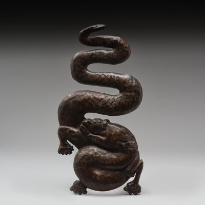 un gros plan d'une sculpture représentant un serpent posé sur une boule